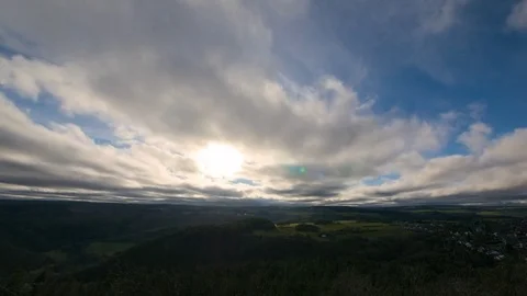 Timelapse of clouds over landscape with hills, forest, fields and rural village Stock Footage 83825916