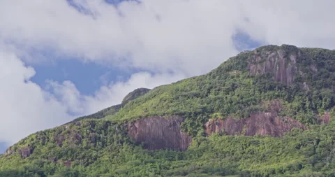 Timelapse of clouds over rocky hill covererd in lush, green vegetation, daytime Stock Footage 236540825