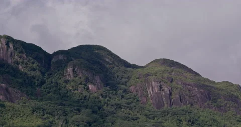 Timelapse of clouds over rocky hill covererd in lush, green vegetation, daytime Stock Footage 236540909