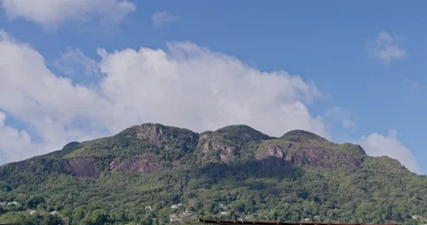 Timelapse of clouds over rocky hill covererd in lush, green vegetation, daytime Stock Footage 236541401
