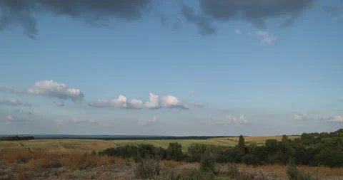 Timelapse of clouds over rolling hills with farmland on a sunny day Stock Footage 253489654