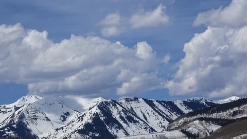 Timelapse of clouds over snow-capped mountain top at mid-day Stock Footage 107693709