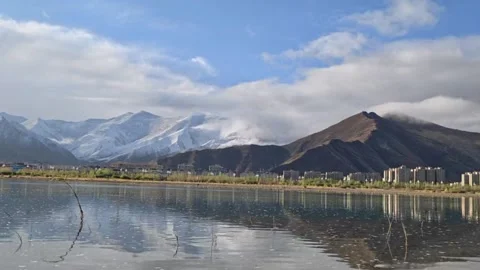Timelapse Clouds Over Snow Mountains And City By The Lake Vídeo Stock 334762165