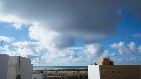 Timelapse Of Clouds Rolling Over Buildings And Sea During Summer Stock Footage 70799503