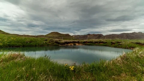 Timelapse of clouds rolling over Geothermal warm pool surrounded by grass field Stock Footage 73011487