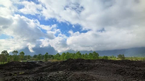 Timelapse of clouds rolling over green trees and the dark volcanic soil Stock Footage 337350829