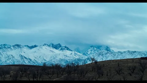 Timelapse of clouds running around snowy mountains. Middle Asian peaks of Tian S Stock Footage 329997398