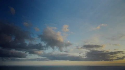 Timelapse - Cloudscape above a calm sea at dawn. bluish and golden colors. Stock Footage 87216404