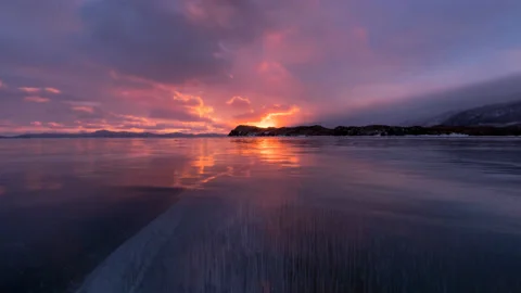 Timelapse cloudy sunset in the icy Lake Baika and deep crack with bubbles Stock Footage 146451415