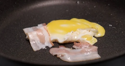 Timelapse of cooking breakfast, frying fried eggs with bacon, sprinkle spices Stock Footage 120896602