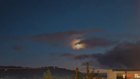 Timelapse crescent moon peeks through clouds in serene night sky Stock Footage 320476869