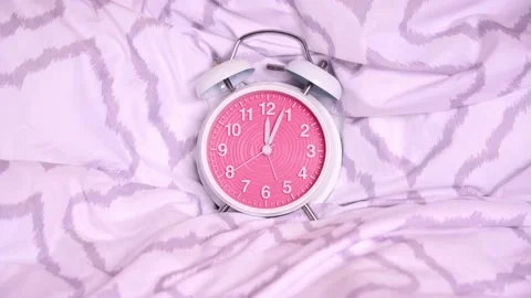 Timelapse of a cute old-fashioned alarm clock on modern bed sheets Stock Footage 150396924