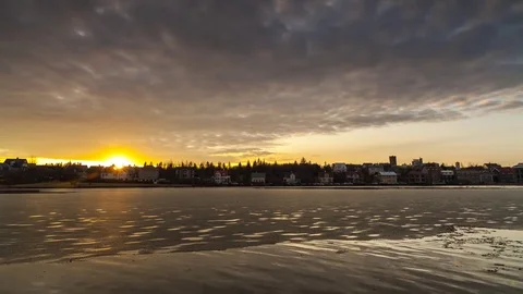 Timelapse of dark clouds rolling over the lake and city houses at sunset Stock Footage 73011575