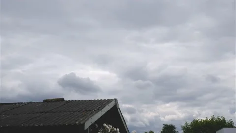 Timelapse of dark storm clouds above the roof of an old weathered shed 動画素材 196703121