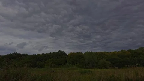 Timelapse of Dark Storm Clouds Passing Over Meadow as Sunlight Breaks Through Stock Footage 344462990