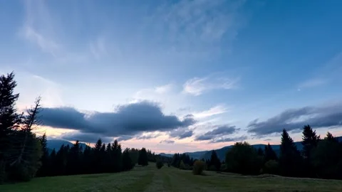 Timelapse, disappearing clouds at dusk over a forest landscape with meadows in Stock Footage 306061950