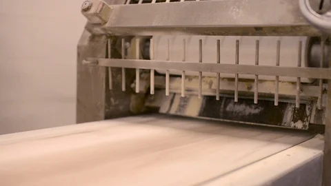 Timelapse of dough exiting a rolling machine crushing it into flat circles Stock Footage 107049316