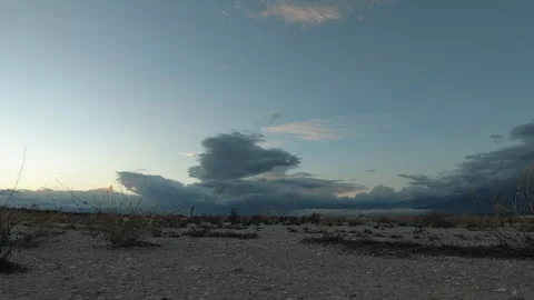 Timelapse dramatic cloudy sky over a barren desert at dusk Stock Footage 293730611