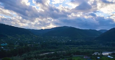 Timelapse of dramatic sunset clouds moving over the mountains, village b-ground Stock Footage 206456558