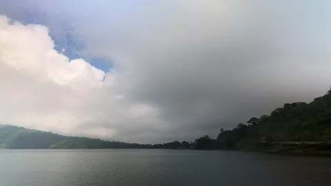 Timelapse of dramatic white clouds rolling over a tranquil lake Видео 347204862