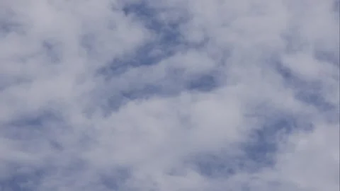 Timelapse of drifting clouds moving across a clear blue sky above an open horizo Stock Footage 343382499