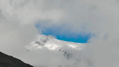Timelapse of drifting clouds revealing snowy mountain peak Stock Footage 317834182