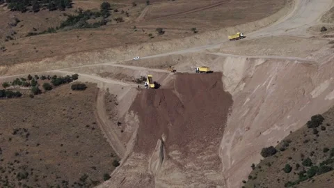 Timelapse of dump trucks hauling soil across open pit mine - Mineral Extraction Vídeos de archivo 339366687