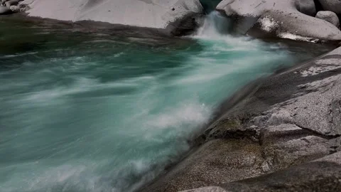 Timelapse of emerald mountain river rushing past large boulder Stock Footage 346246331