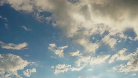 Timelapse of evening clouds moving with sun shining on blue sky Stock Footage 142704321