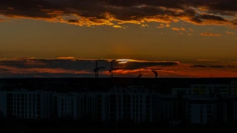 The timelapse of the evening sunset over construction cranes and houses against  Video stock 170556219