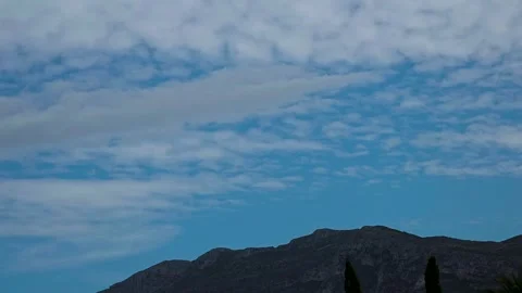 Timelapse of fast moving white clouds floating over Montgo mountain ridge in Stock Footage 345172554