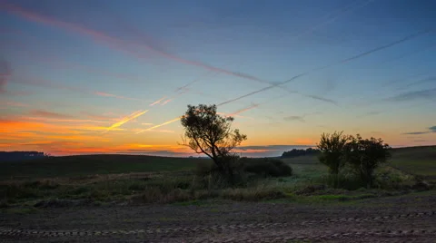 Timelapse of fields under sunset sky with chemtrails 库存影片 58933281