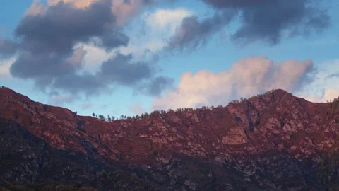 Timelapse of floating clouds over rocky mountains illuminated by setting sun Stock Footage 182377009