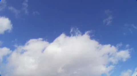 Timelapse of fluffy white clouds drifting across a blue sky overhead 動画素材 32961442