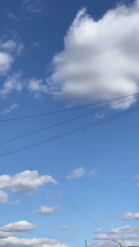 Timelapse of fluffy white clouds moving across a blue sky with power lines .. Stock Footage 333928624