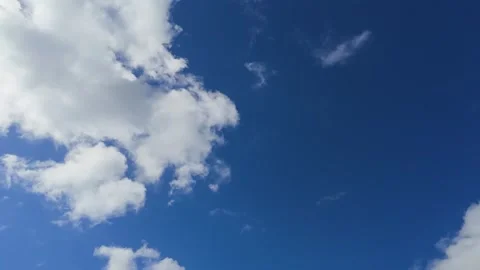 Timelapse of fluffy white clouds moving across bright blue sky on a sunny day 库存影片 342994975