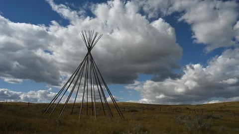 Timelapse of fluffy white cumulus clouds above a dry prairie scene with a teepee Stock Footage 310690669