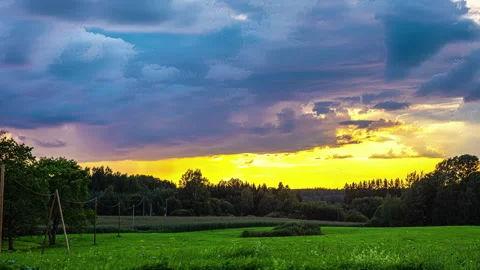 Timelapse footage of moving clouds in above a green landscape with dark Stock Footage 256636357