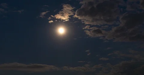 Timelapse of full moon hiding behind clouds. Clouds passing by warm moonlight Stock Footage 129868816