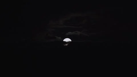 Timelapse of Full Moon rising through clouds in night sky Video stock 243970603