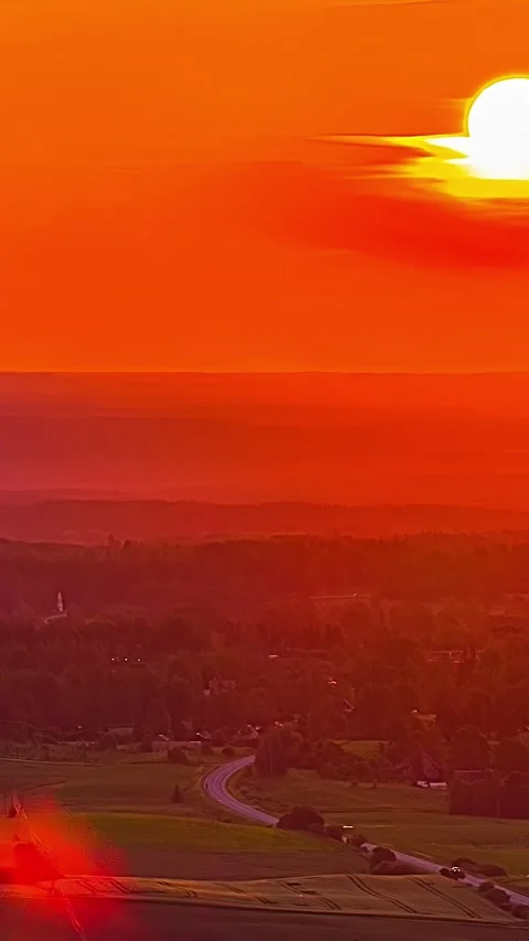 Timelapse of giant glowing sun setting over winding rural road and latvian Stock Footage 332619069