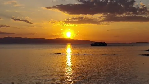 Timelapse - Golden Hour over open waters with a ferry boat passing Stockbeeldmateriaal 334700818