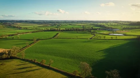 Timelapse Green fields in countryside with moving clouds under golden sunlight. Stock Footage 303568881