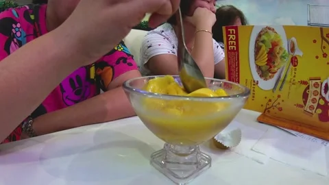 Timelapse of a group people sharing eating mango desert on a shopping mall Stock Footage 107315622