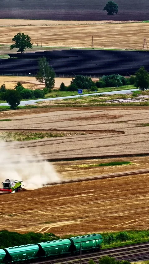 Timelapse of Harvester Operating in Rural Fields Beside Passing Train and Road Stock Footage 336237170
