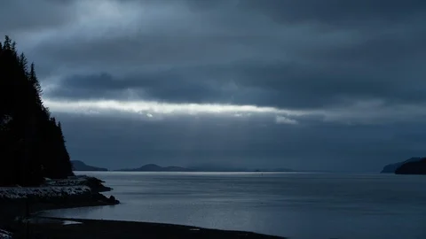 Timelapse of heavy clouds passing above sea with sunbeams peaking through them Stock Footage 129114358