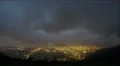 Timelapse of heavy mountain clouds, lights of night city lying below near sea 4k or 4k+ Resolution
