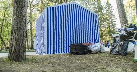 Timelapse on how people make out a light shopping canvas tent in a park Stock-Footage 129540811
