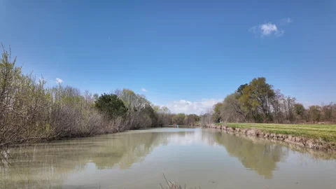 Timelapse of irrigation pond with blue sky and scattered clouds Stockbeeldmateriaal 337180210