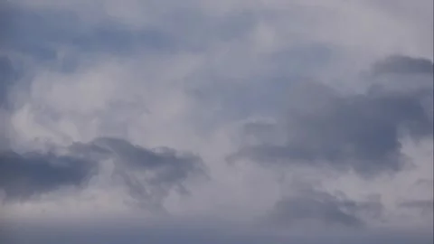 Timelapse of layered clouds drifting across a clear blue sky, slowly covering an Видео 341863764